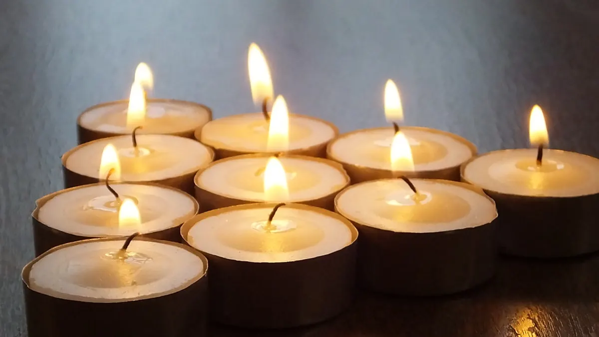 Een groepje brandende waxinelichtjes dicht bij elkaar op een donkere tafel