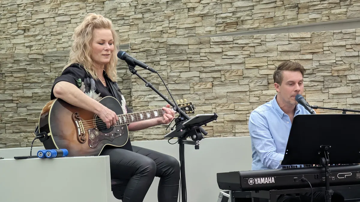 Een zangeres met akoestische gitaar en een pianist spelen samen als duo