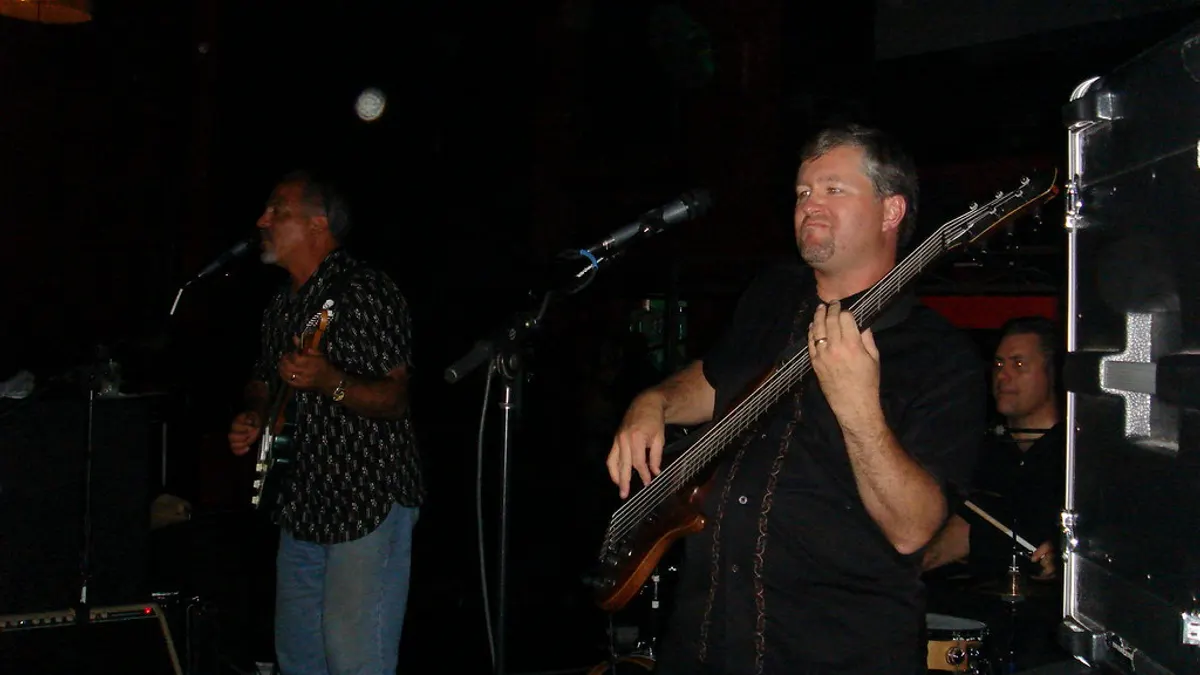 Een bassist en een gitarist van een liveband spelen samen op een sfeervol verlicht podium