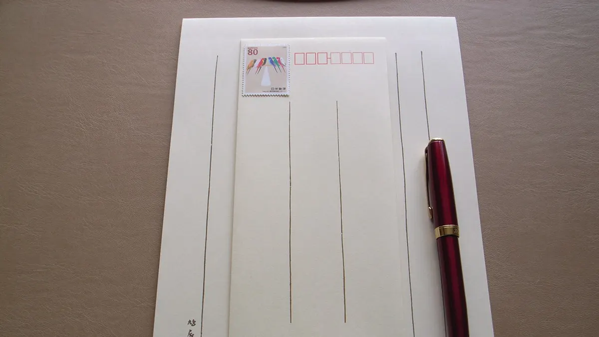 Blanco briefpapier met een gefrankeerde envelop en een rode vulpen