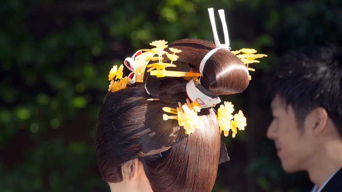 Achterkant van een bruid met een gladde opgestoken knot, versierd met gele bloemen en haarspelden