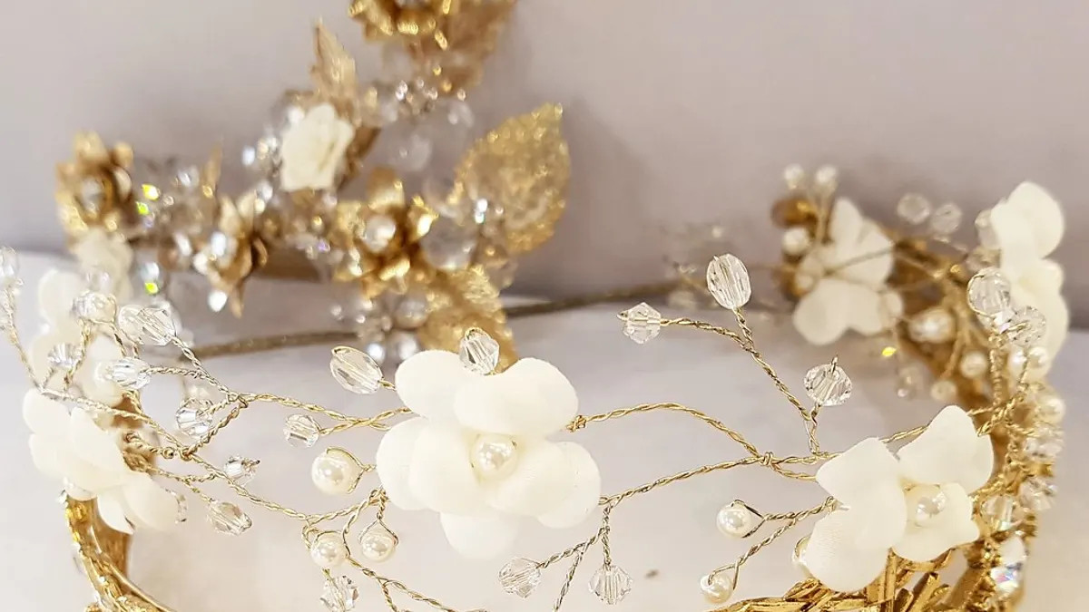 Gouden haarkroon met witte bloemetjes, parels en kristallen voor een bruidskapsel