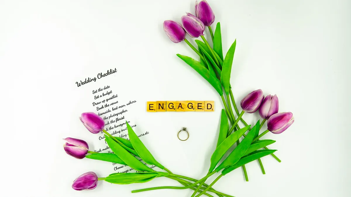 Trouwchecklist naast het woord engaged in letterblokjes, een verlovingsring en paarse tulpen