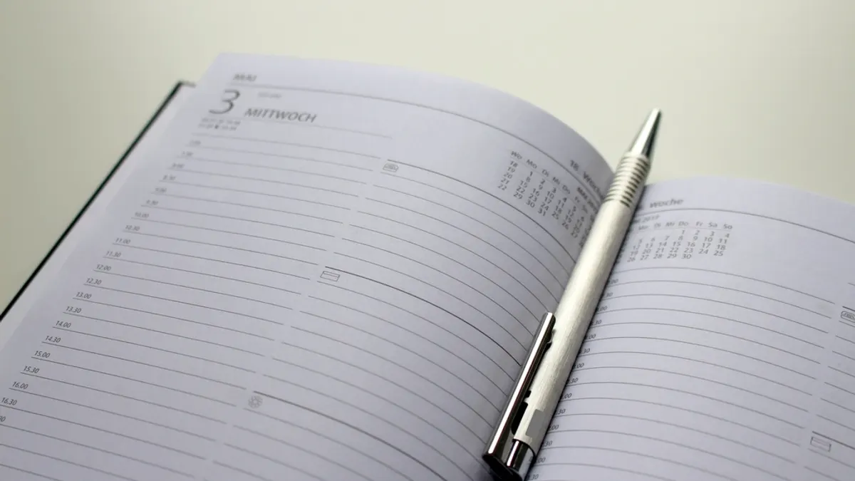 Een opengeslagen dagagenda met een lege dagpagina en een zilveren balpen ertussen