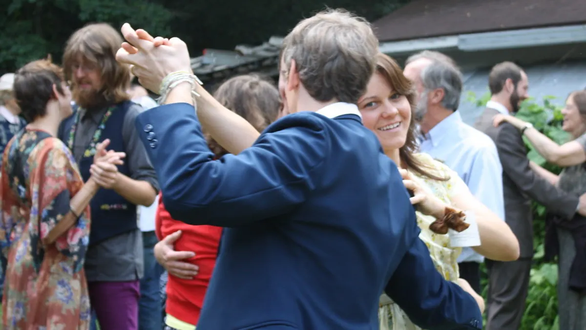 Gasten dansen in paren op een trouwfeest in de tuin