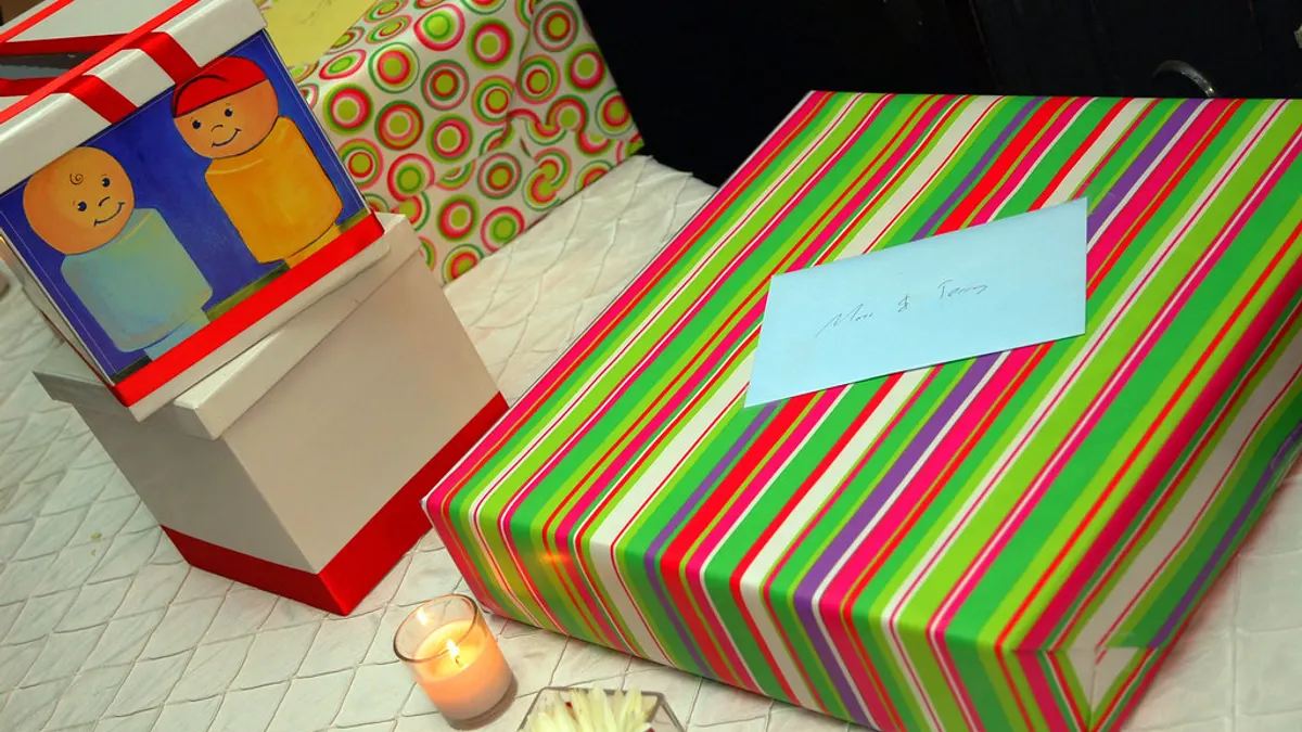 Ingepakte cadeaus op een cadeautafel, met een blauw kaartje op een gestreept pakje en een brandend kaarsje ervoor