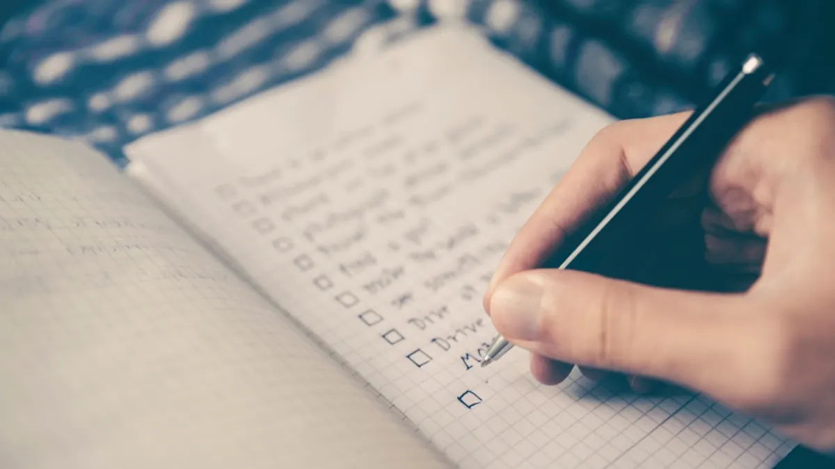 Hand die taken afvinkt op een checklist in een open notitieboek
