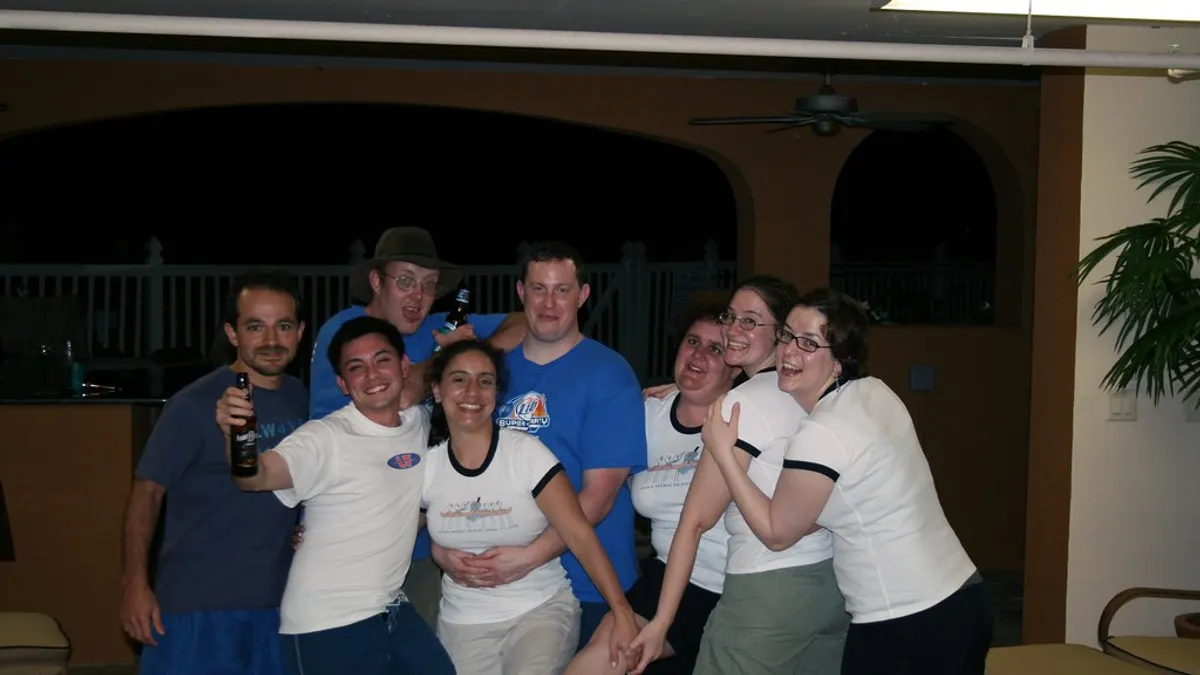 Groepje lachende vrienden in T-shirts poseert samen op een avondfeest