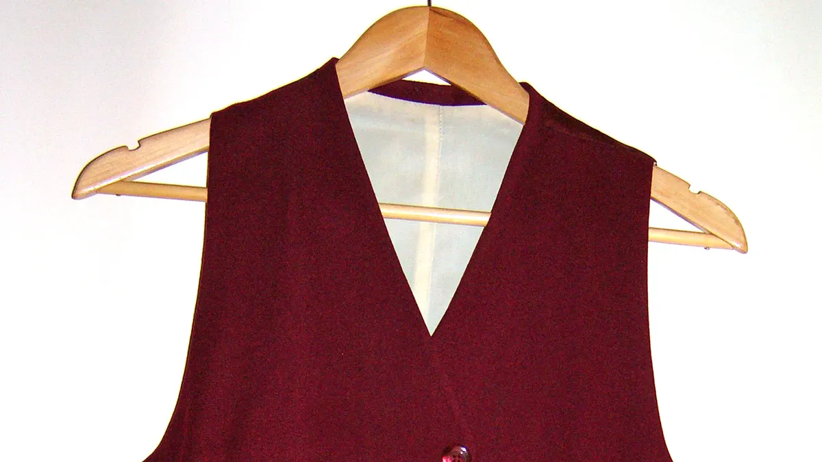 Bordeauxrood gilet met stoffen knopen aan een houten kleerhanger