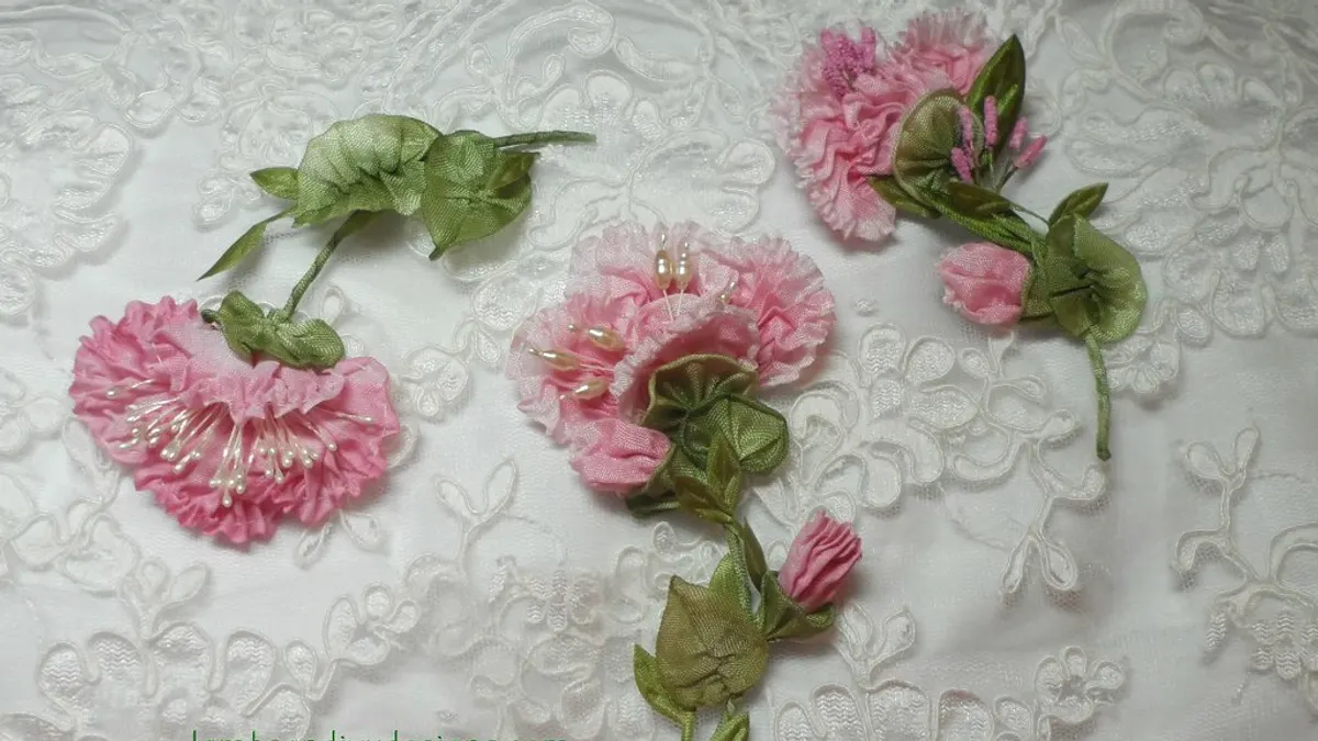 Geborduurde roze bloemen van lint met groene blaadjes op wit kant