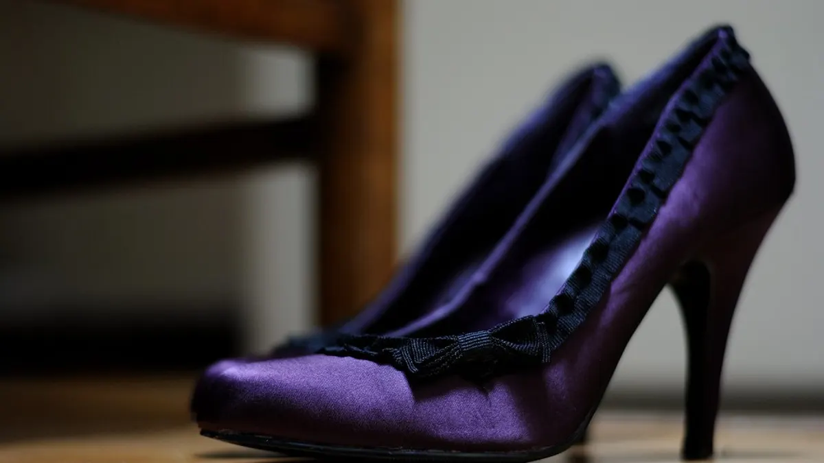 Paarse satijnen pumps met een zwart randje op een houten vloer