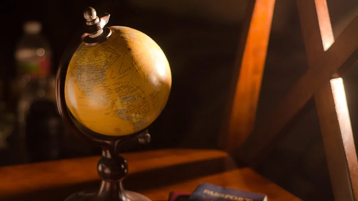 Een kleine wereldbol en een paspoort op een houten tafel in warm licht