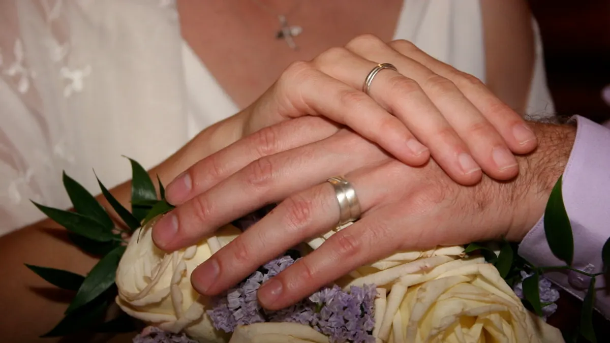 Twee ringen en een klein handboeket op de tafel van een gemeentehuis