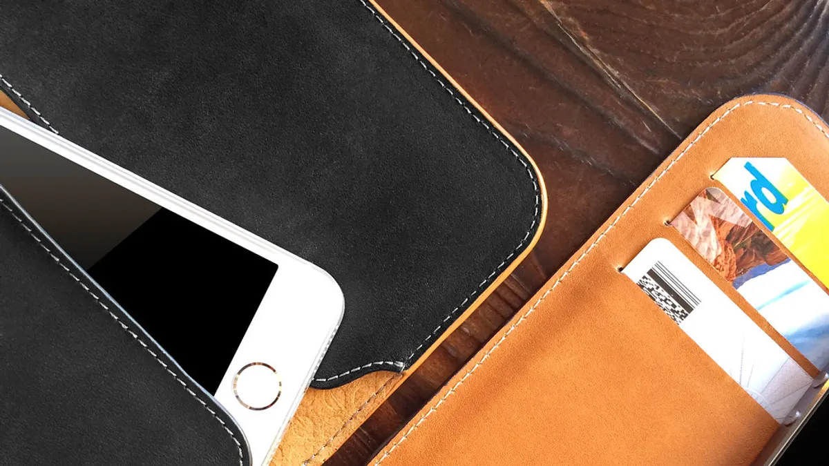 Leren portefeuille met bankkaarten naast een smartphone op een houten tafel