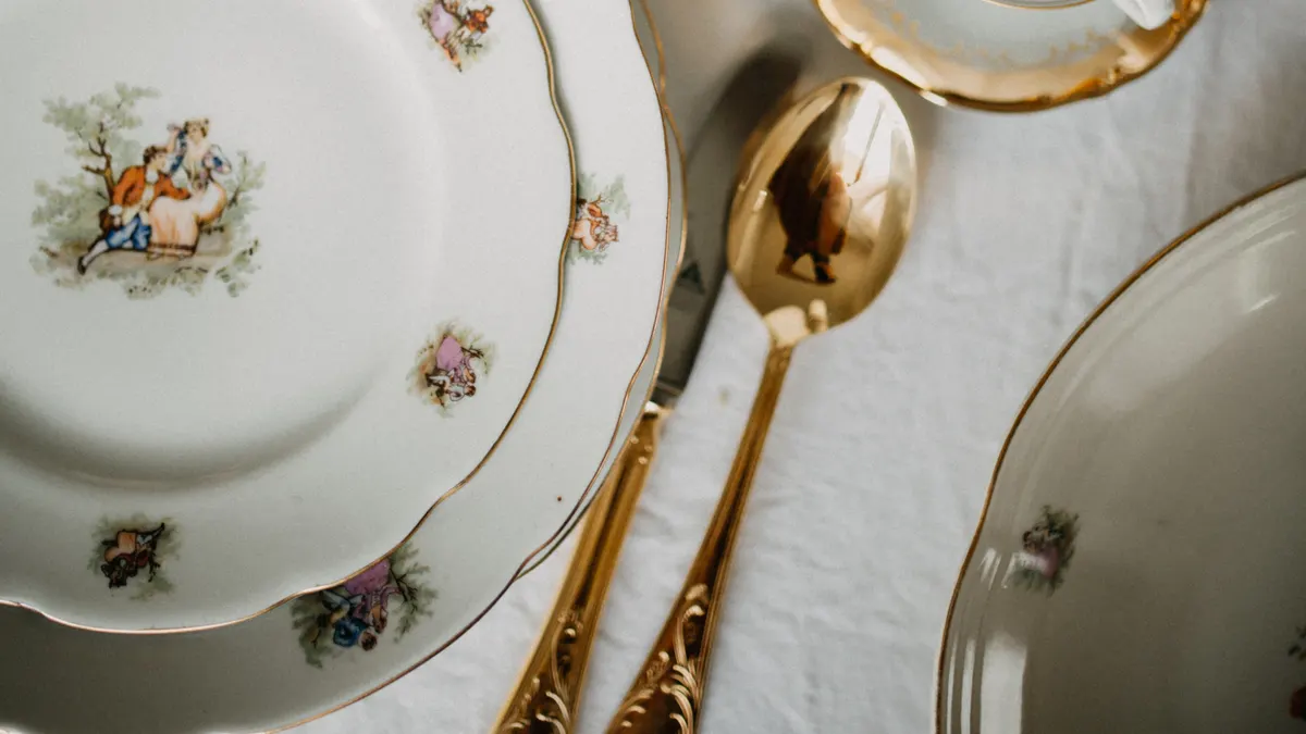 Vintage porseleinen borden met bloemmotief en vergulde lepels op een wit tafellaken