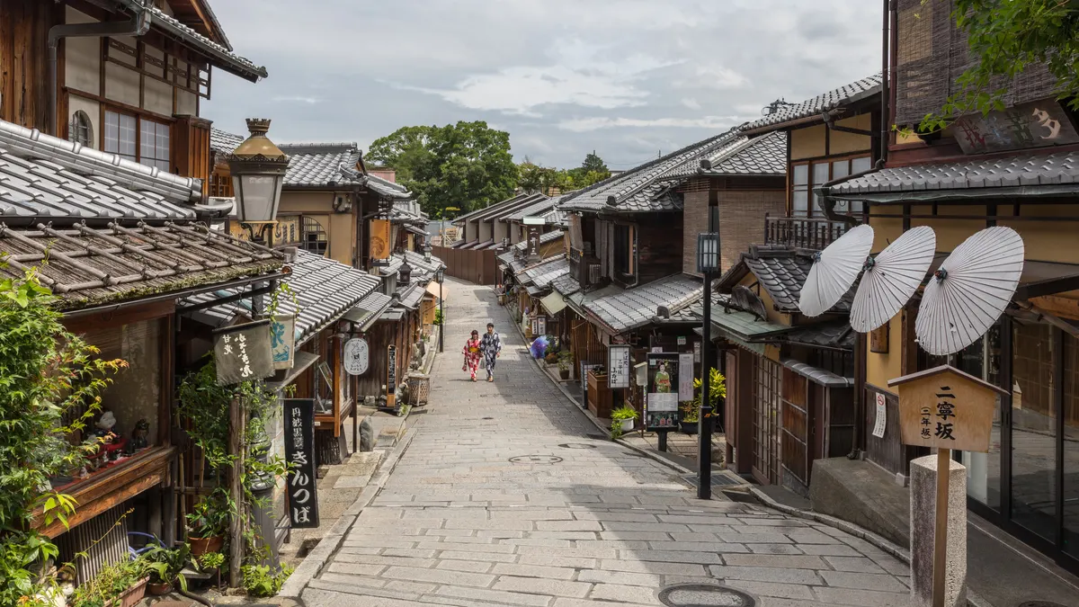 Een rustige straat met houten huizen en papieren parasols in Kyoto, met een koppel in yukata