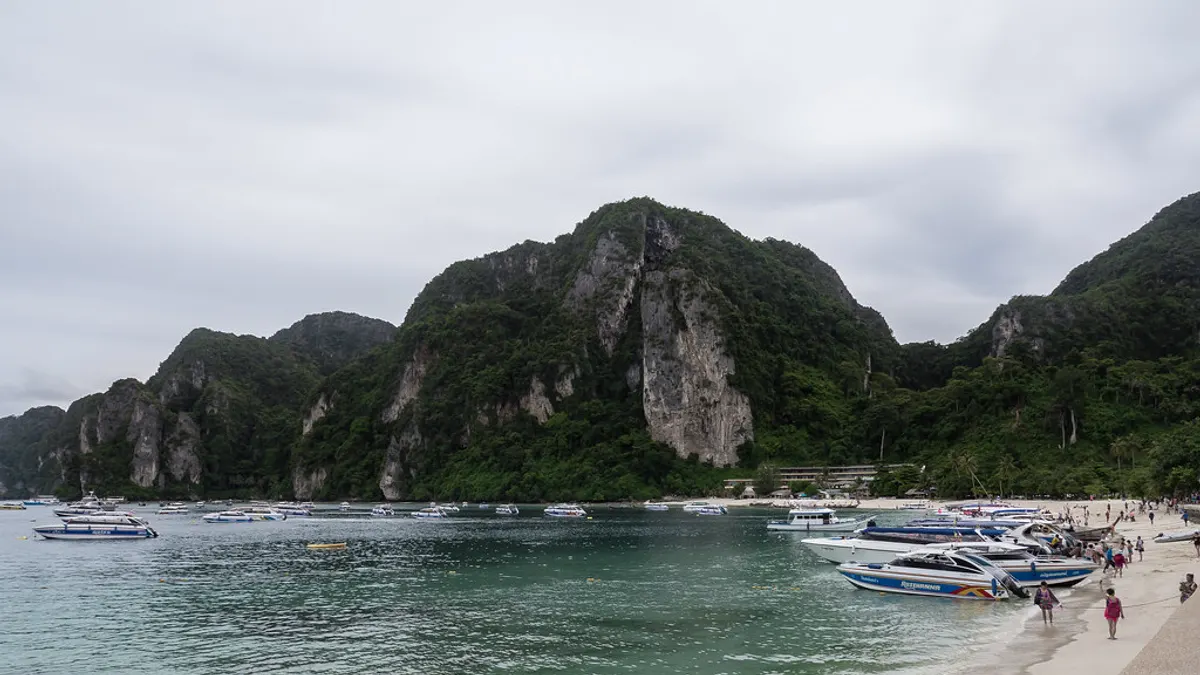 Een baai met beboste kalkstenen rotsen en bootjes op Koh Phi Phi in Thailand