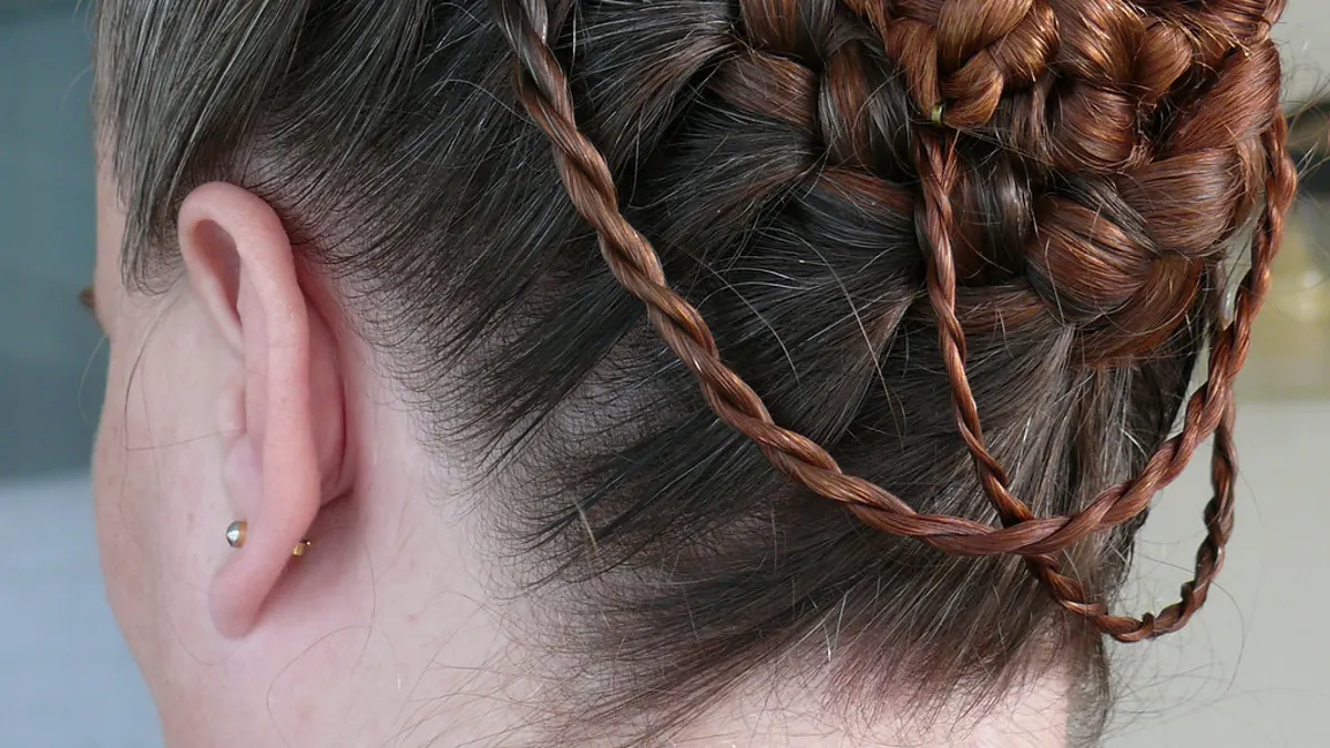 Close-up van een opgestoken kapsel van achteren, met dunne vlechten rond een gevlochten knot