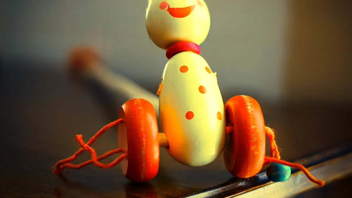 Houten trekdiertje met oranje wieltjes als speelgoed voor de kinderen op het feest