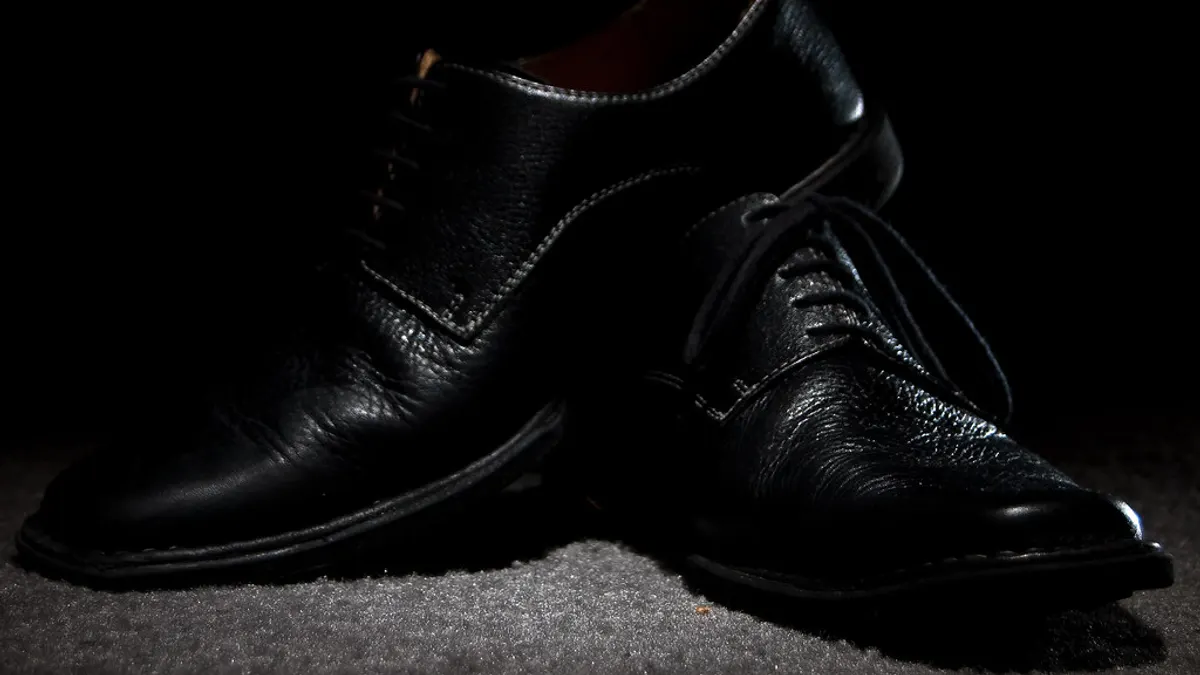 Een paar glanzende zwarte herenschoenen in een smalle lichtbundel, klaar voor de dansvloer