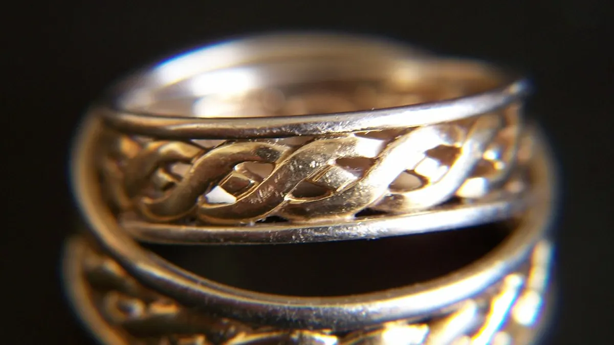 Twee gouden trouwringen met een gevlochten motief van dichtbij