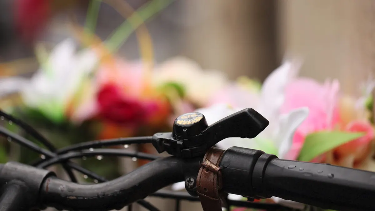 Het stuur van een fiets met een mand vol bloemen erachter