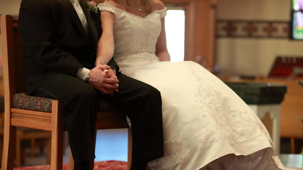 Bruid en bruidegom zitten hand in hand naast elkaar tijdens een kerkelijke ceremonie
