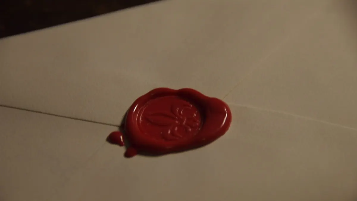 Een witte envelop gesloten met een donkerrood lakzegel, klaar om te versturen