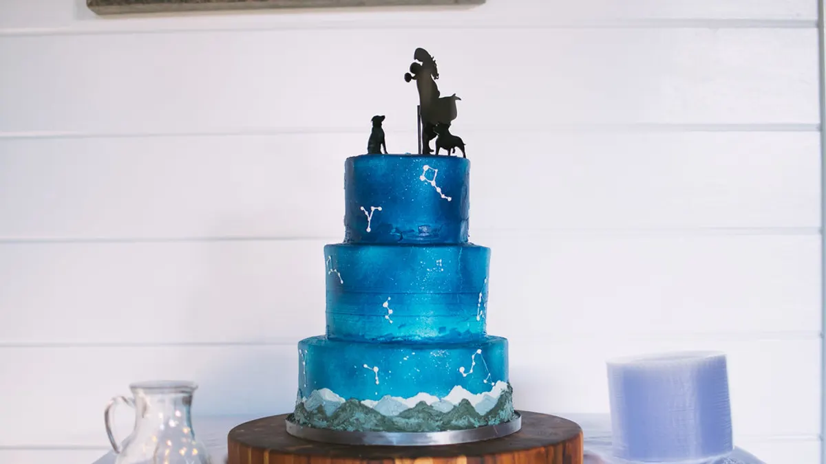 Blauwe drielaagse bruidstaart met sterrenbeelden en silhouetten als taarttopper