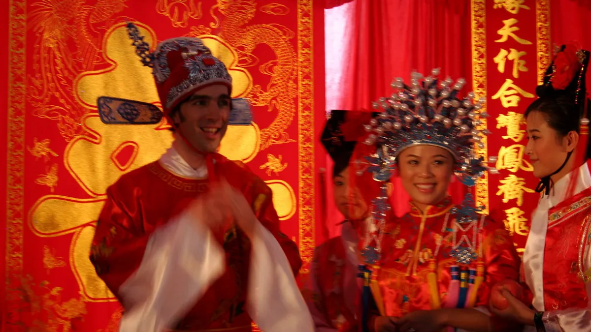 Bruidspaar in rode traditionele Chinese trouwkledij met versierde hoofdtooi