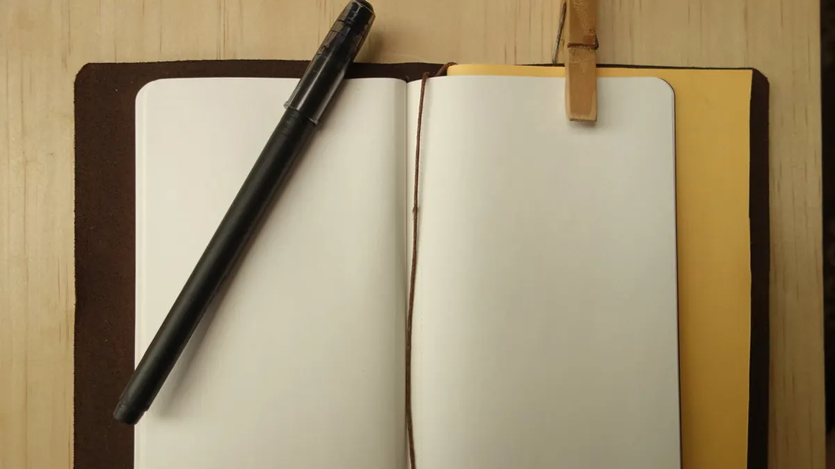 Open notitieboek met een pen op een houten tafel, klaar om het trouwbudget in uit te schrijven
