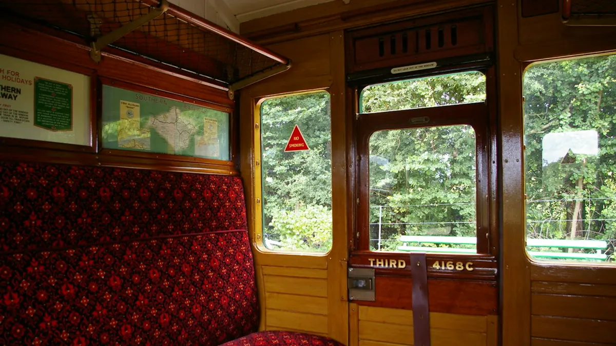 Een coupé van een historisch treinrijtuig met houten wanden en rode banken
