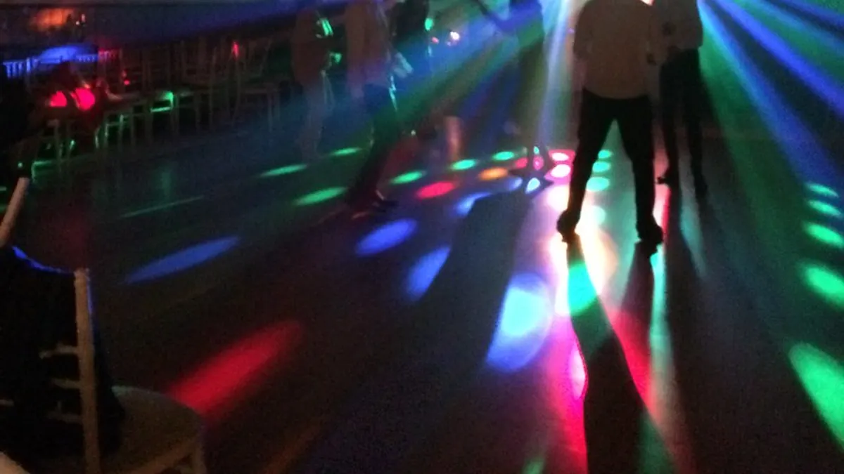 Volle dansvloer met feestende gasten en sfeerverlichting op een trouwfeest