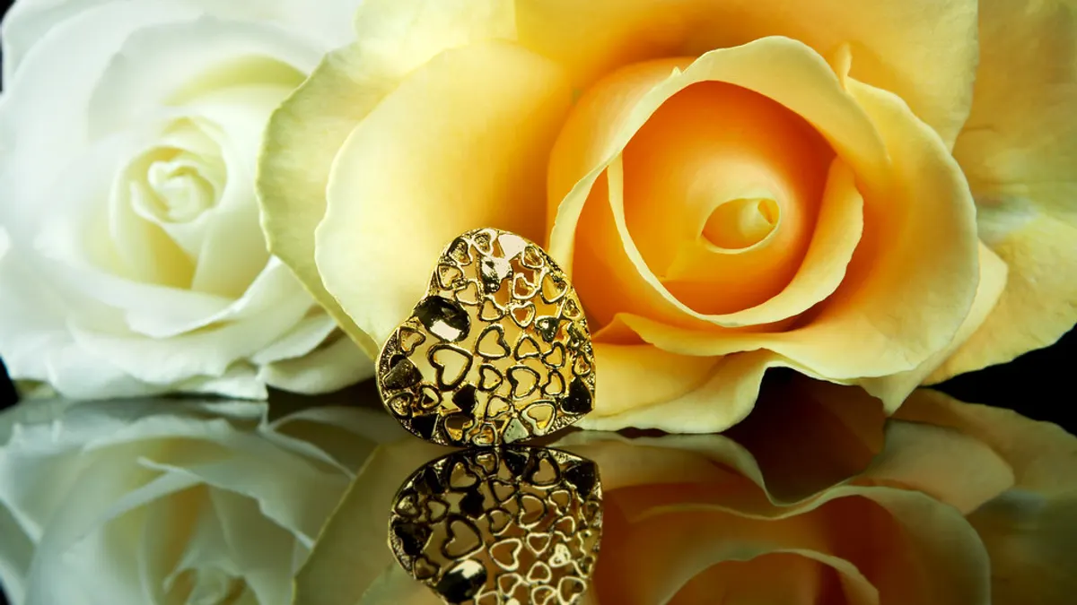 Een gouden hartje voor twee crèmekleurige rozen, als cadeau voor een gouden bruiloft