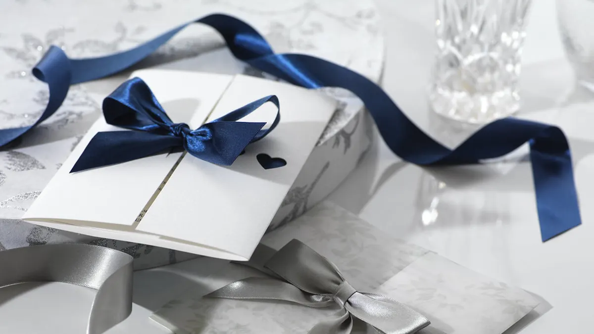 Witte trouwkaart dichtgestrikt met een donkerblauw satijnen lint