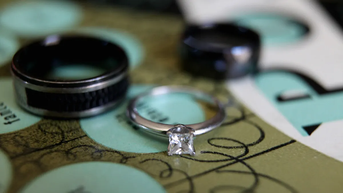 Twee zwarte herenringen en een verlovingsring met diamant op gekleurd papier
