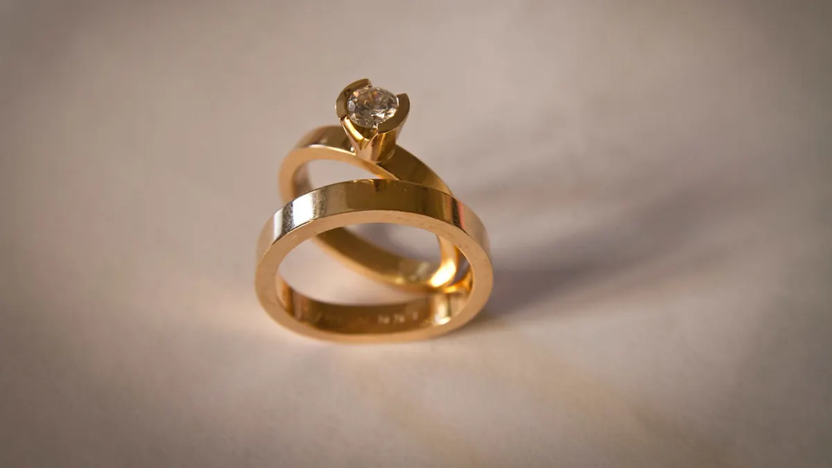 Een gouden verlovingsring met diamant op een bijpassende trouwring