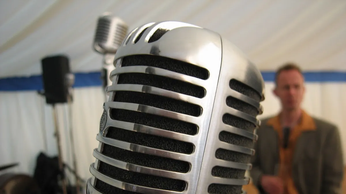 Klassieke zilveren microfoon in een feesttent met een spreker op de achtergrond