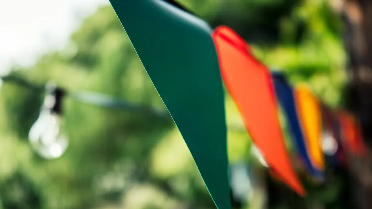 Kleurrijke vlaggetjes en een lichtsnoer hangen klaar voor een feest in de tuin