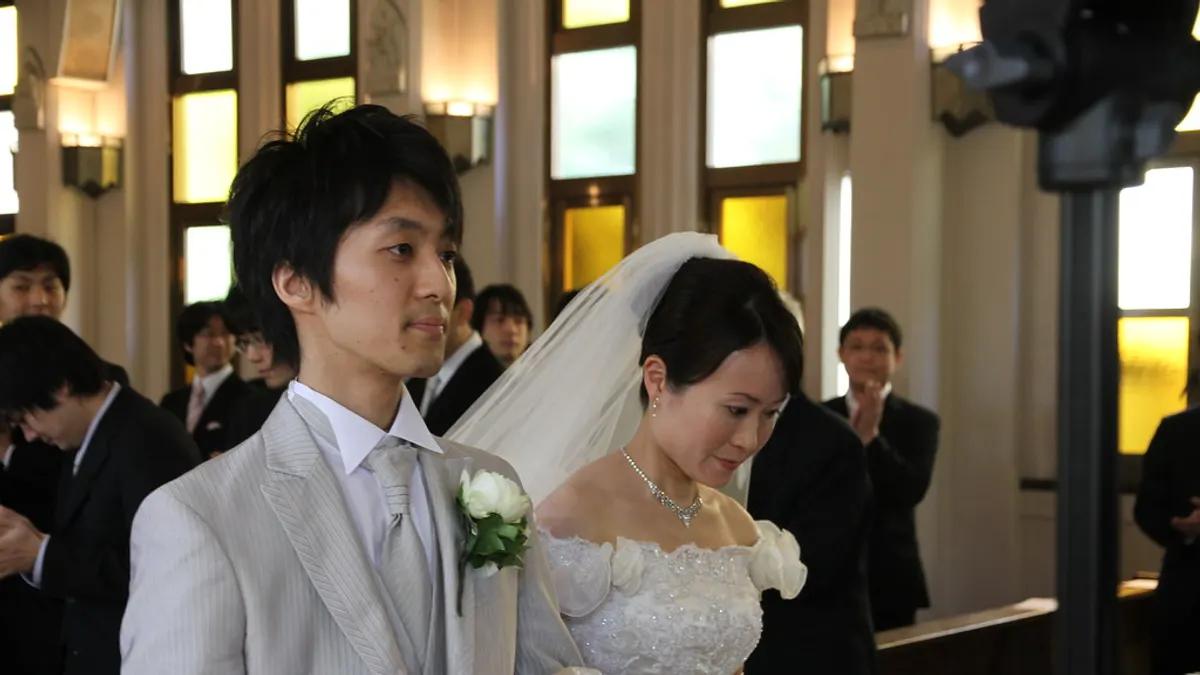 Een vriend leidt een buitenceremonie met een map in de hand voor het bruidspaar