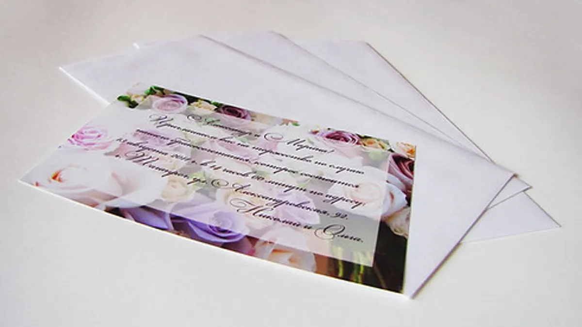 Een trouwuitnodiging met bloemenmotief en twee witte enveloppen klaar om te versturen