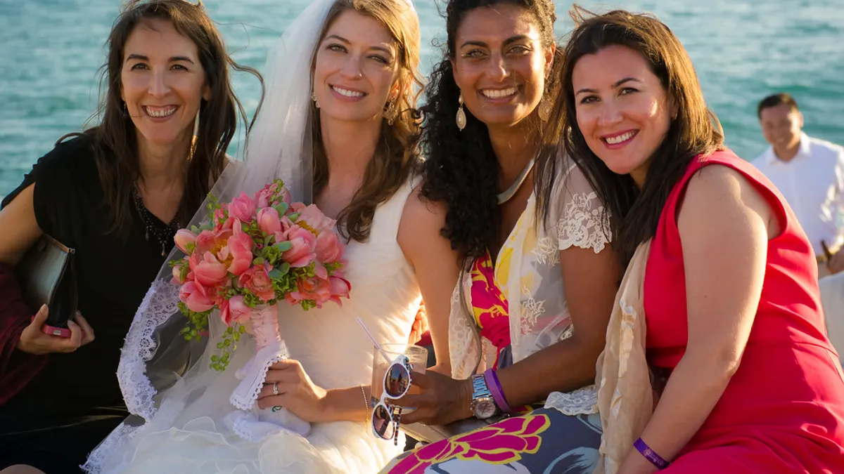 Bruid met roze boeket poseert met drie vriendinnen op een boot