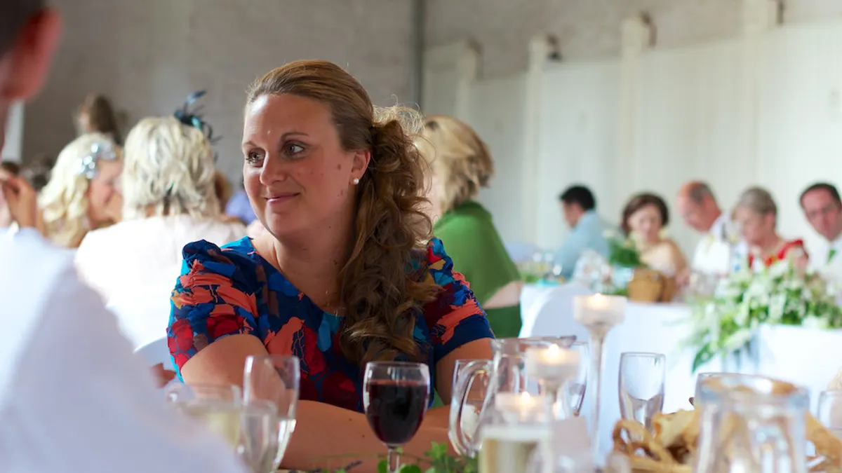 Bruidspaar zit aan een eigen tafeltje met zicht op de ronde gastentafels