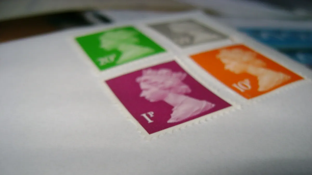 Vier gekleurde postzegels op een witte envelop, van dichtbij gefotografeerd