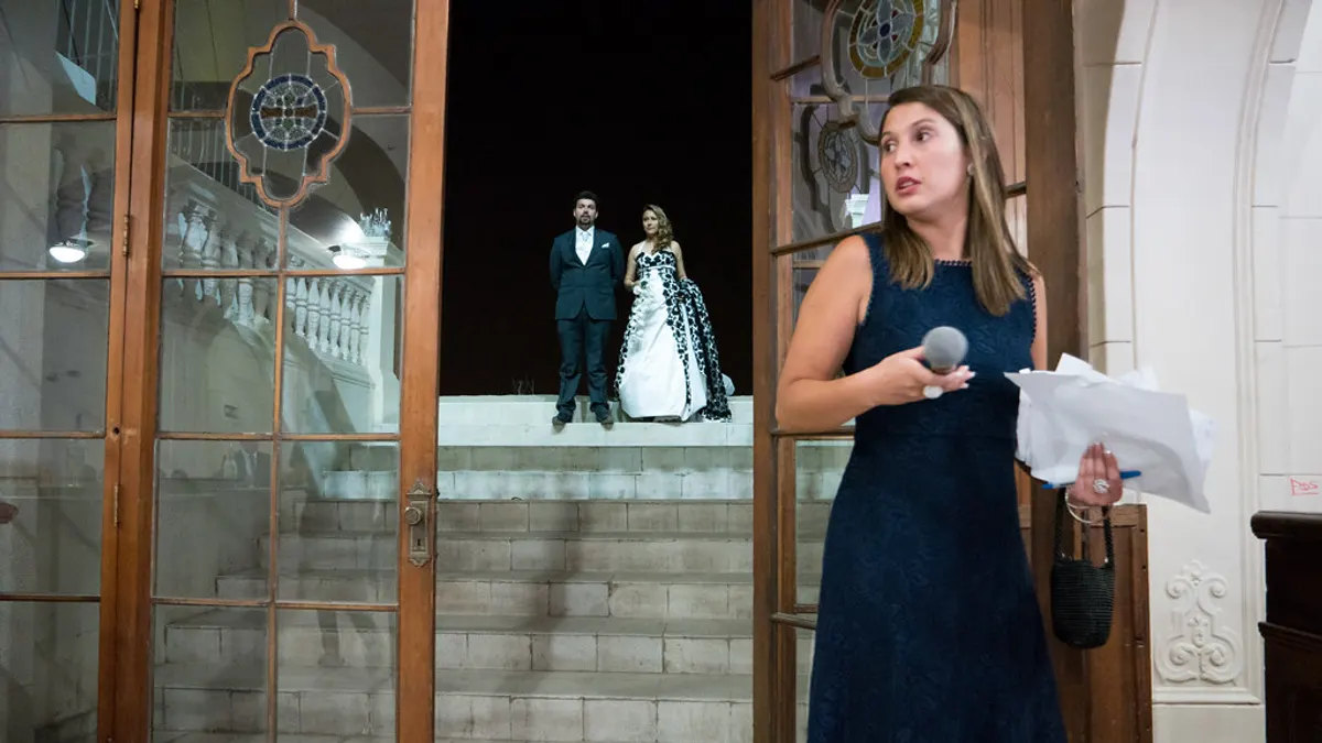 Weddingplanner met microfoon en draaiboek leidt de entree van het bruidspaar in